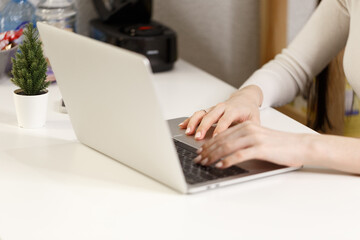 A girl student learning distance training course study work at home office. Young women's hands typing on a laptop, close-up. The girl is working on a laptop on white working desk