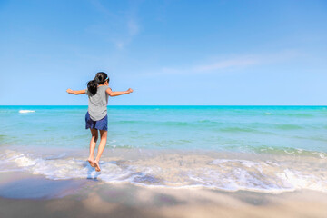 Asian kid girl jump playing jump on the beach with turquoise blue sea