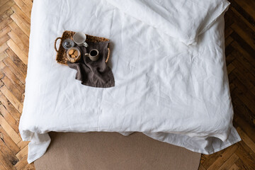 wooden tray with light breakfast on bed on bed with white linen
