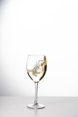 Weißwein im Weinglas mit weinspritzer aus dem glas