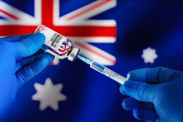 Injecting dose of vaccine in syringe for Covid-19 over the Australian flag. Preparing vial of...