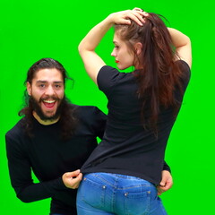 Attractive european woman and young latin man smiling cheerfully stand on the green chroma key background. There is a blank space for advertising content on the girl's shirt's. Relationships, couple.