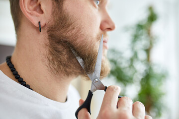 Close up of Handsome man in white t-shirts cutting beard, moustache personally himself