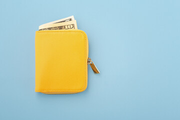 Yellow wallet with cash on blue background