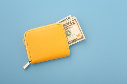 Money in yellow wallet on blue background