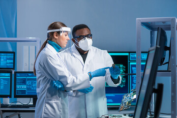 Diverse team of microelectronic engineers discuss current developments in a science lab. Workplace...