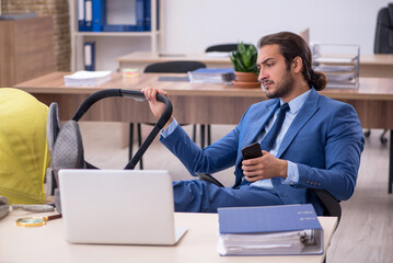 Young male employee looking after new born at workplace