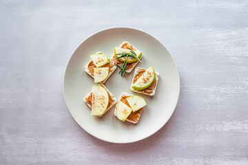 Healthy breakfast with peanut butter and apple sandwiches on rice cakes. Top view on grey concrete...