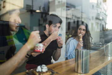 Amigos chicos y chicas tomando helado en la barra interior de una heladeria