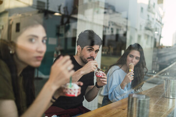 Amigos chicos y chicas tomando helado en la barra interior de una heladeria