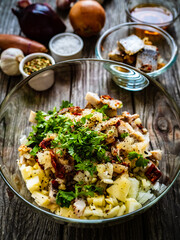 Marinated herring fillets with pickled cucumber, parsley, onion and apple on wooden table

