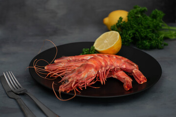 Three 3 grilled giant river prawn on black plate, dark gray stone table.