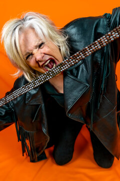 Funny Portrait Of Mature Woman. Beautiful Lady Have Fun As A Rock Star Dressed In Leather