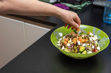 Close up view of woman putting grapefruit in salad salad bowl. Healthy eating concept.