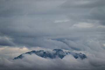 Winter photograph of a large mountain surrounded and isolated by the dense clouds of those days when Filomena was lurking all over Spain.