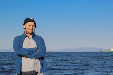A man in a hat against the backdrop of a seascape.