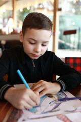 Child drawing with pencils in restaurant