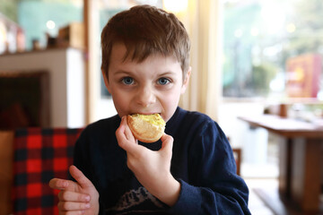 Child eating bun with butter in cafe