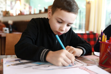 Kid drawing with pencils in cafe