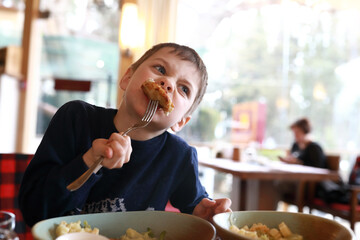 Kid eating cutlet in restaurant