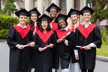 Diverse international students with diplomas celebrating graduation, smiling at camera