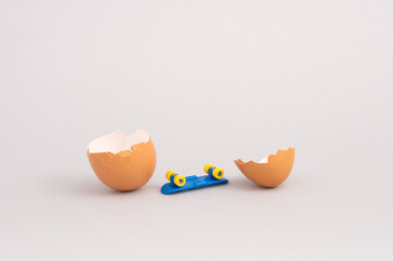 Creative minimal composition with broken egg and skateboard on grey background