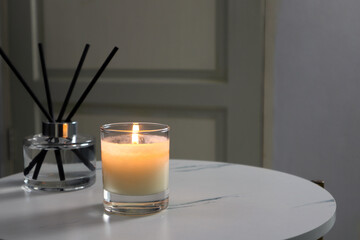 luxury lighting aromatic scented candle is on the mable table with reed diffuser to creat romantic and relax ambient in the grey bedroom with background of grey wooden door on valentine day