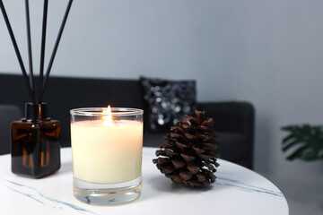 luxury aroma lighting aromatic scented candle glass displayed on white marble table to creat romantic and relax ambient on valentine day with background of grey sofa in living room at night 