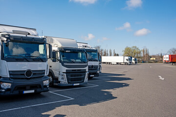 white trucks on parking lot in good weather. Transport company vehicles waiting at a truck stop. 