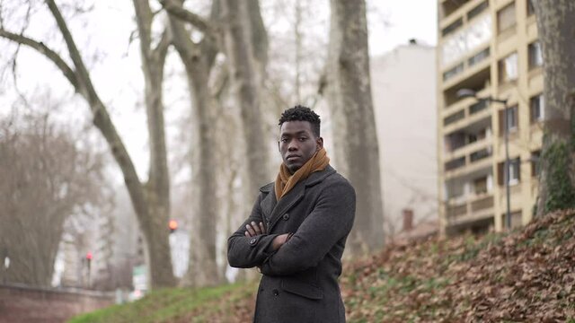 Young black man standing outside wearing coat and scarf looking at camera portrait