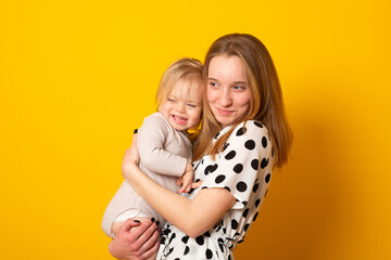Sister teenager with baby sister smiling on a yellow background. Adorable cheerful sisters of different ages.