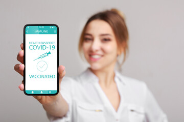 Woman showing smartphone with Immune digital passport for covid-19