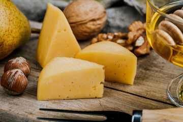 Cheese dish with organic cheeses, fruits, nuts on a wooden background. Delicious cheese snack