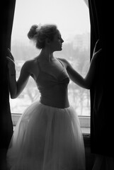 Young and graceful ballerina in pointe shoes and a tutu dances in the studio. Choreography and dancing classes concept. Creative ideas of ballet posing, performance. Black and white photo. 