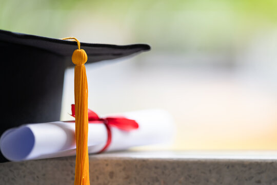 Close-up of a mortarboard and degree certificate put on table. Education stock photo