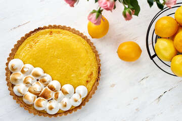 Tart with lemon curd with merenga decor on a light wooden background.