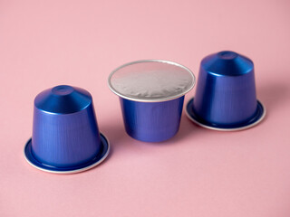 purple aluminum capsules with ground coffee on a pink background are lined up in a row