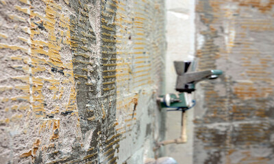 Selective focus. Old grungy concrete wall with defocusing shower faucet  as background or texture. Bathroom reparations