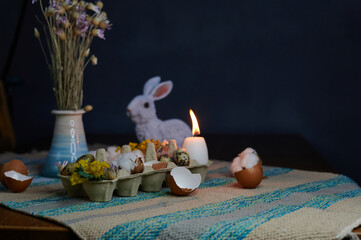 Easter decor in an egg box with dried flowers and candles with a hare