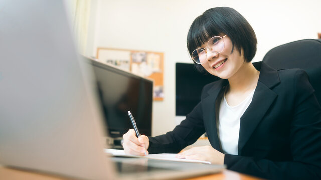 Young adult asian woman using laptop computer for video call work at home on day.