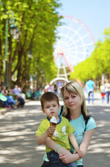 Happy family concept. Mother and son are playing in the park,  laughing and eating ice cream on a spring walk on a sunny day. Family holiday and togetherness, selective focus. 
