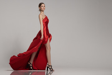 fashion woman strides in long red dress - obrazy, fototapety, plakaty