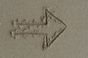 Line drawing on the sand beach. Arrow symbol pointing to the right in the sand.