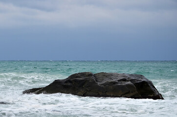 large stone in the sea. Mainly cloudy