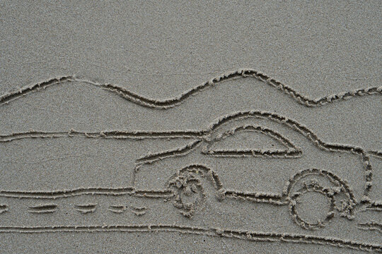 Line drawing on the sand beach of car driving on the road with nature of mountain.