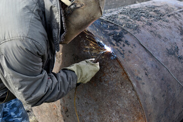 A worker welding an iron pipe with a protective mask