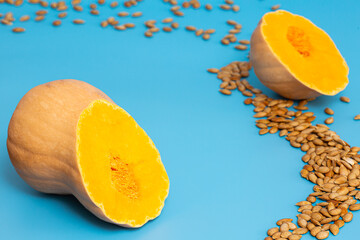 On a blue background, cut pumpkin and scattered roasted seeds.