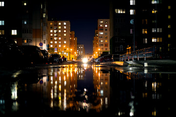 Fototapeta na wymiar Night life, modern buildings of the capital with the reflection of light in puddles.