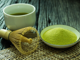 close up green tea, matcha power and whisk a cup of hot green tea on wooden table.traditional japanese drink