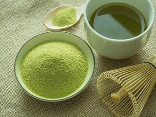close up green tea, matcha power and whisk a cup of hot green tea on wooden table.traditional japanese drink